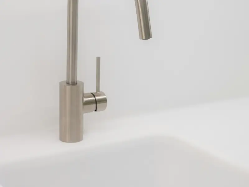 Brushed-steel kitchen faucet over a white sink